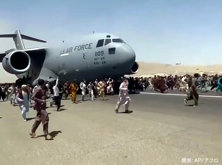 タリバンが首都カブールを掌握した翌日、アフガニスタンからの出国を求めて滑走路を移動する米軍の輸送機とともに走る人々。数百人もの人々がカブール国際空港に駆けつけた(2021年8月16日、カブール国際空港)