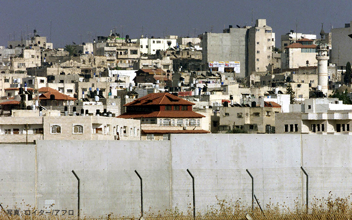 イスラエルがガザに建設した分離壁。2002年6月19日、ウエストバンクシティ。An Israeli-built wall separates off the West Bank city of Tulkarem, June 19, 2002.REUTERS/Gil Cohen Magen